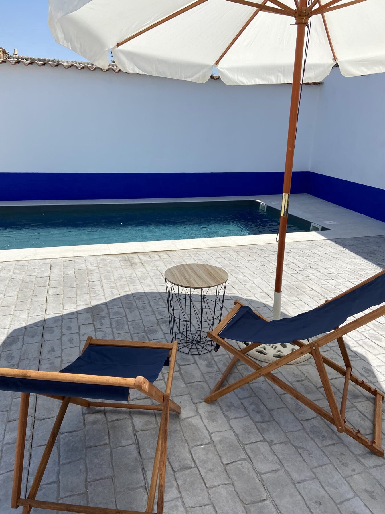 Piscina de la casa con tumbonas y sombrilla